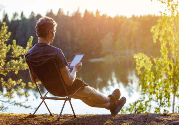 Ein Mann liest ein eBook am See.