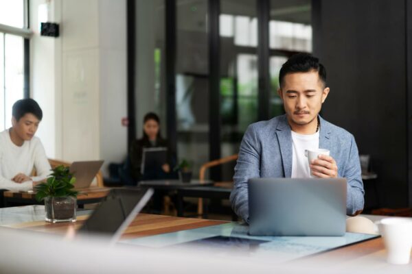 Businessperson working on laptop and drinking coffee in cafe