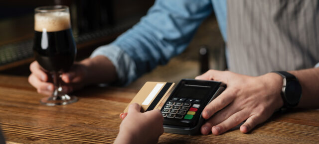 Frau bezahlt mit Kreditkarte kontaktlos in britischem Pub