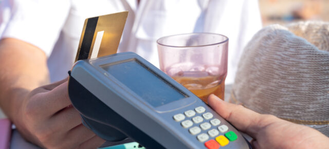 Mann bezahlt mit Kreditkarte am Strand